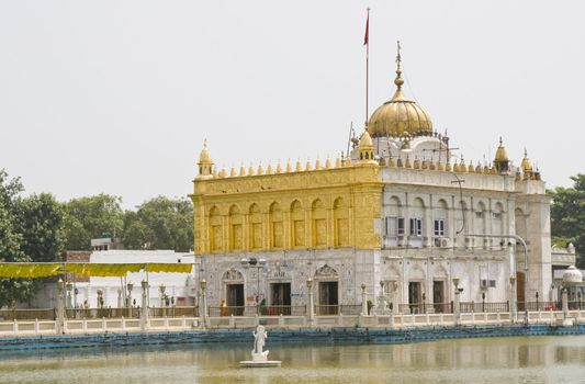 Durgiana Hindu Temple. White marble building with gold dome set in artificial lake. Amritsar, Punjab, India