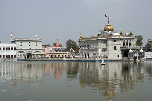 Durgiana Hindu Temple. White marble building with gold dome set in artificial lake. Amritsar, Punjab, India