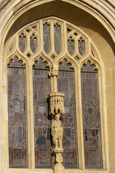 Stain glass window and religious statue decorating historic Bath Abbey in Bath, Somerset, England. Historic Georgian style building built of locally mined bath stone.