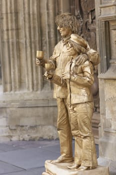 Street artists posing as statues dressed in golden costume seeking money from tourists in Bath, Somerset, England.