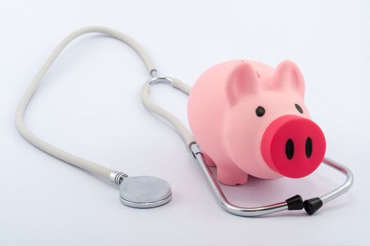 Piggy bank and stethoscope on white background