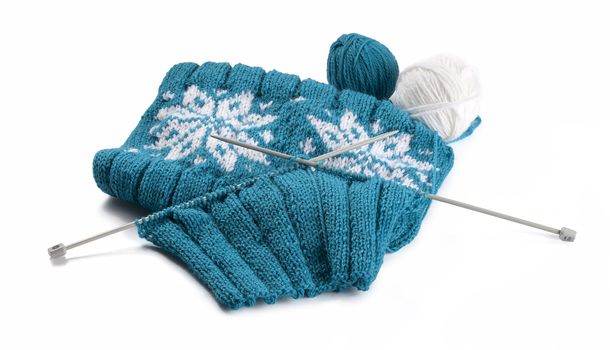 Turquoise knitting with clews and knitting needles on the white background