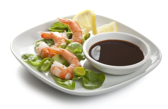 Three boiled shrimp's tails with leek, lettuce, lemon and soy sausage on the white plate