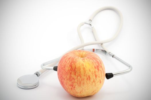 Using stethoscope to examine an apple on white background