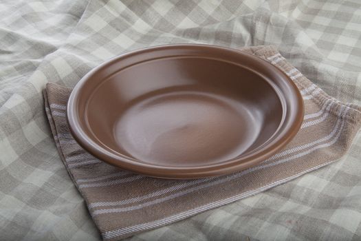 Empty brown bowl ob the striped linen napkin