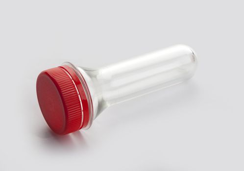 Plastic bottle preform with red cap on the grey background