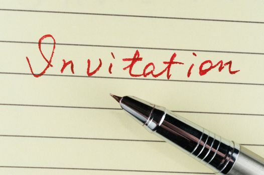 Invitation word written on lined paper with a pen on it