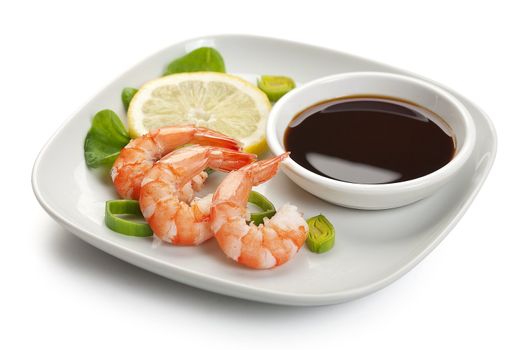 Three boiled shrimp's tails with leek, lettuce, lemon and soy sausage on the white plate