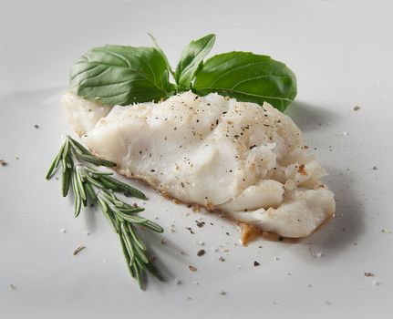 Fried cod with basil and rosemary on the white