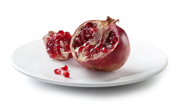 One braked red pomegranate on the white plate