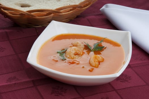 Tomato soup with shrimps and parsley in the white bowl