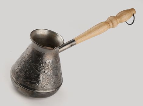Copper coffe pot with wooden handle on the gray
