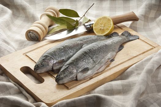 Two trunk of raw trout with lemon and bay leaf on the wooden board