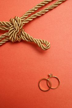 A couple of wedding rings alongside a tied knot for the symbol of marriage.