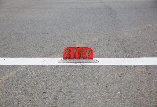 Old style street level stop signattached to center of the lane on a road