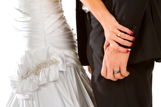 A bride and groom portrait showing only their bodies and their hands against a white background. You can see the wedding rings on the fingers.