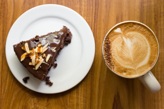 Chocolate cake with white ceramic plate and Cup of Coffee on a wood table