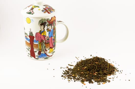 A handful of green leaf tea with jasmine and a mug for tea