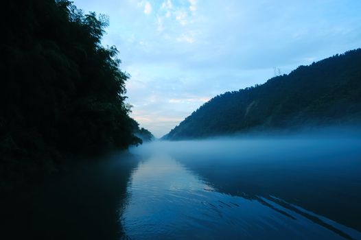 River landscape at sunset with fog rolling across the chilly river water, photo taken in Hunan province of China