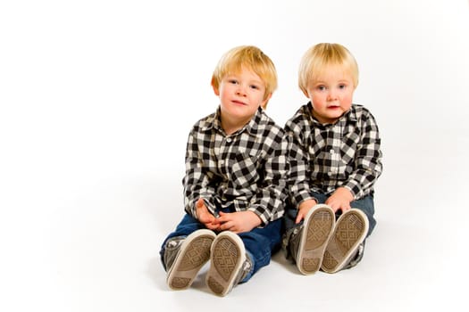 A boy and his sibling brother pose for this portrait in a studio against an isolated white background.