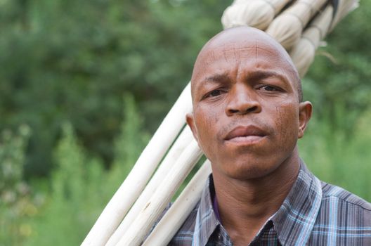 Stock photograph portrait of worred-looking a black South African entrepreneur small business broom salesman in Hilton, Pietermaritzburg, Kwazulu-Natal. Intentional limited depth of field with sharp focus on the eyes.