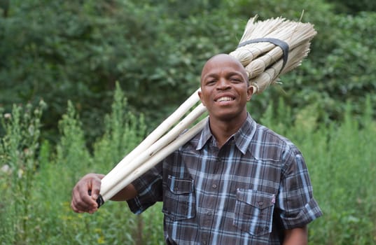 Stock photograph of a smiling black South African entrepreneur small business broom salesman in Hilton, Pietermaritzburg, Kwazulu-Natal