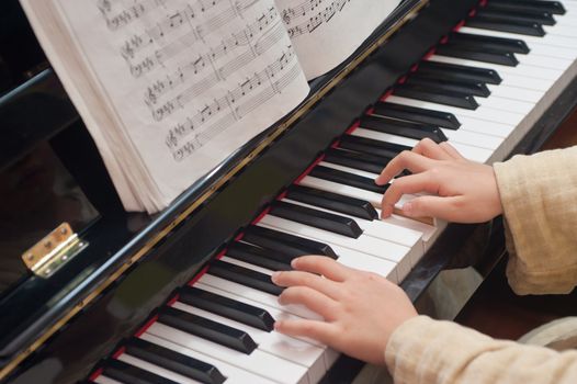 Hands of a little Asian kid learning to play piano