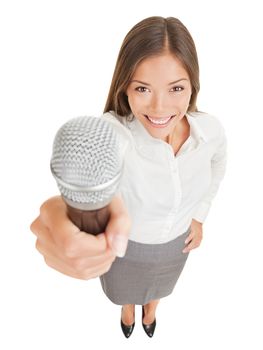 Fun high angle perspective of a beautiful smiling young woman offering up a microphone with her hand raised towards the camera, isolated on white