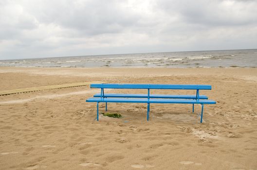 blue bench on sea ocean seaside beach sand in cloudy day.