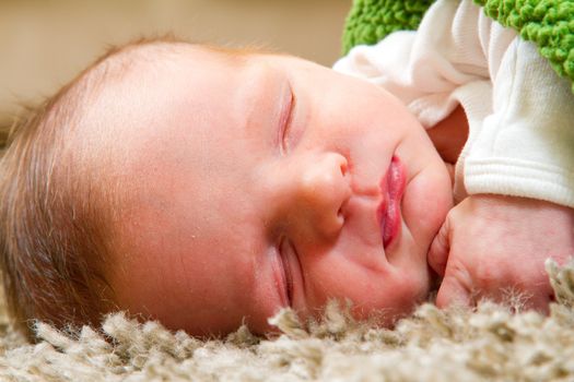 A young newborn baby boy rests wrapped up in a blanket and looking comfortable and cozy.