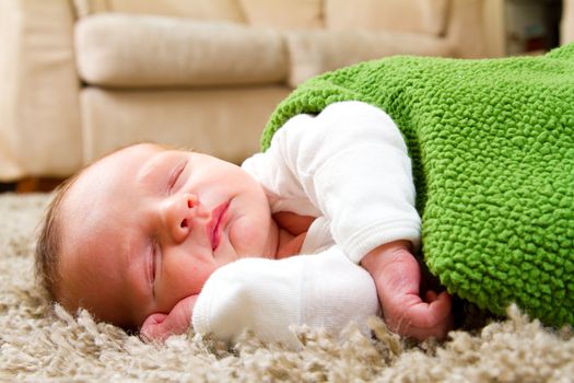 A young newborn baby boy rests wrapped up in a blanket and looking comfortable and cozy.