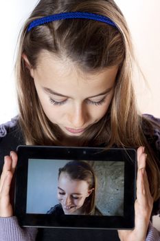 Young girl holding a tablet showing a photo of herself