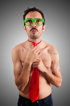 naked man wearing a red tie on gray background