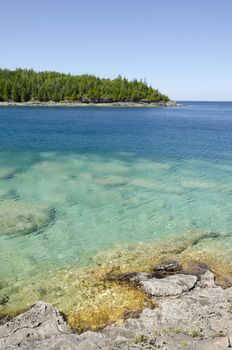 Green and blue water of Huron Lake, Ontario under blue sky.