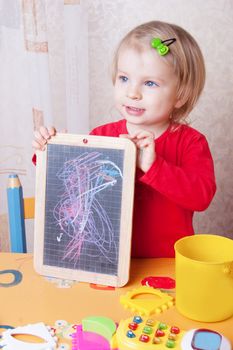 Cute baby girl showing her chalkboard drawings in nusery