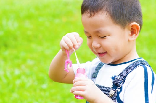 Asian boy blowing bubbles outdoor