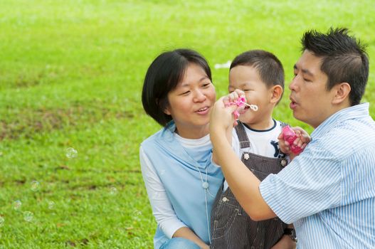 Happy Asian family at outdoors playing bubble wand