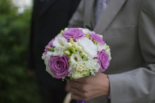 Bunch of flowers in the hand of a groom or man.