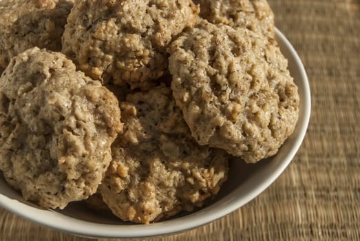 Homemade oatmeal cookies in bowl on reed mat closeup