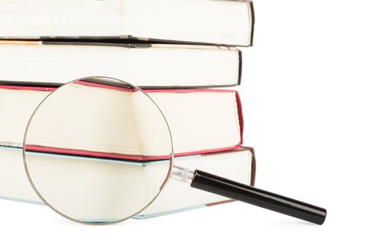 Stack of books and magnifying glass isolated over white background