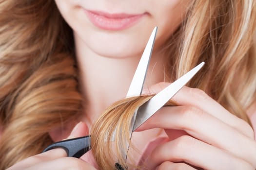 Young woman cutting her hair with scissors