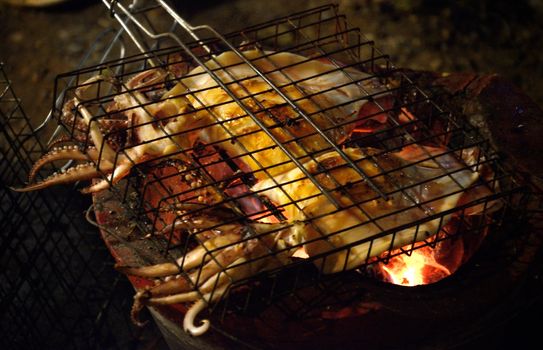 Squid grilling with fire on stove, Cooking concept