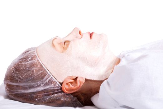 Beautiful woman lying with facial mask on the white background.