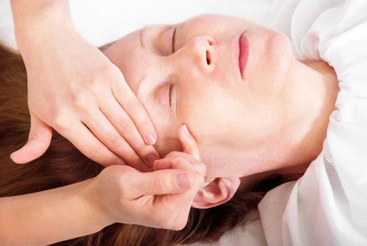 Close-up her face receiving a facial massage.