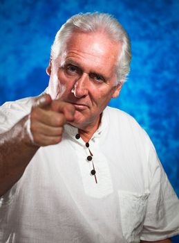 A serious and angry looking man pointing and looking  at camera.