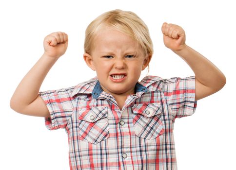 A frustrated and angry young boy with fists raised in the air and pulling a face. Isolated on white.