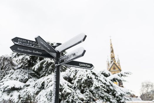 Directions sign in Hyde Park, with Albert Memorial in the background after three days of blizzards.
