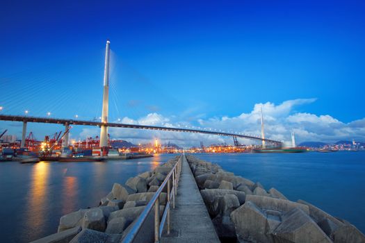 Port warehouse with containers and industrial cargoes , view under bridge on water break at sunset