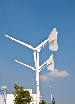 White wind turbine generating electricity on blue sky