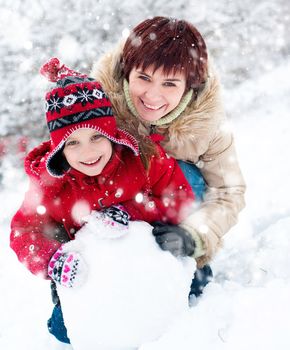 Smiling mother and daughter with snowman